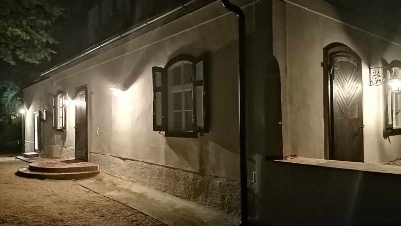 Osvetlená budova v noci s otvorenými oknami a dverami.