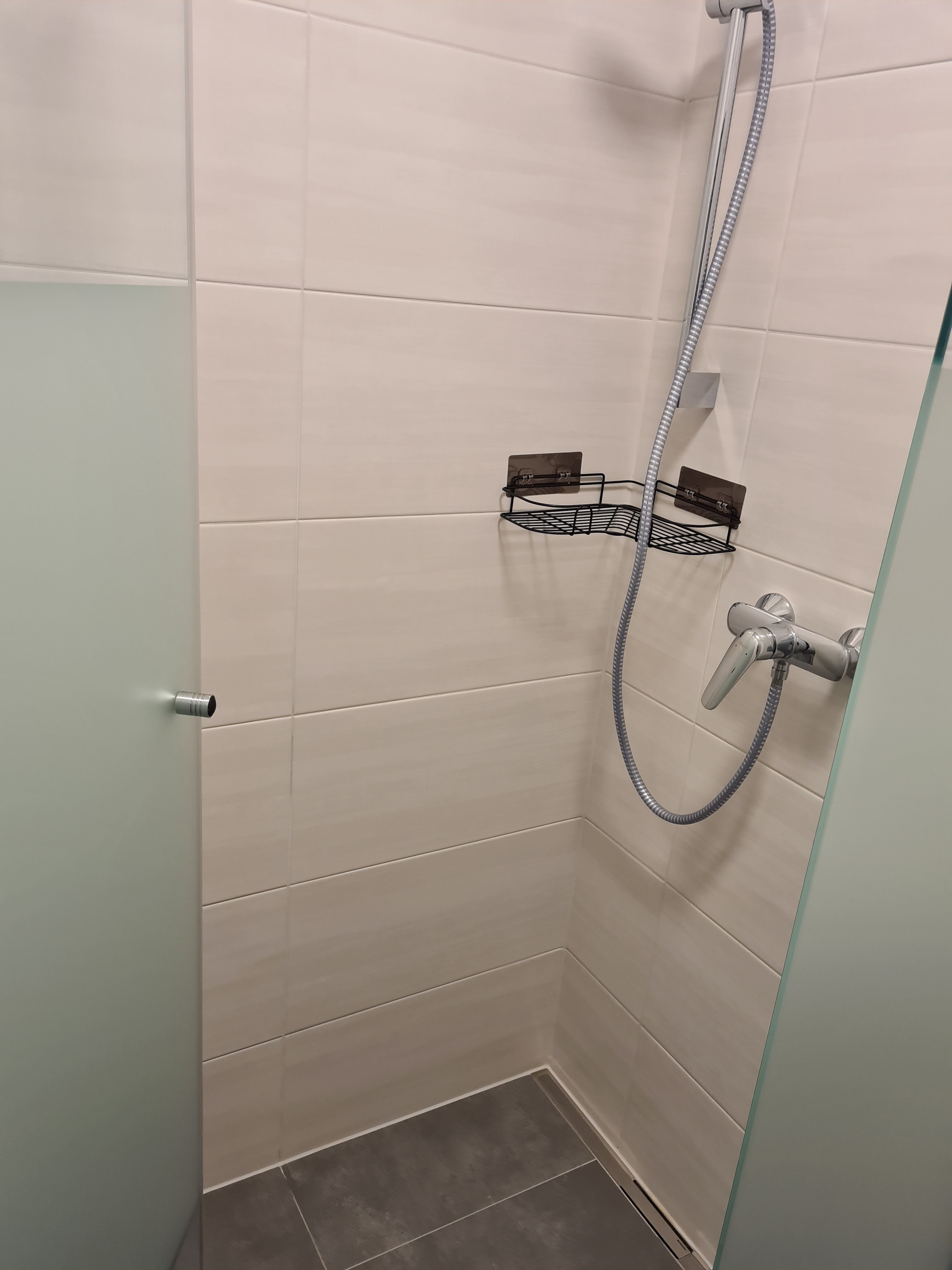 Moderná sprcha so sklenenou stenou a sprchovou hlavicou.