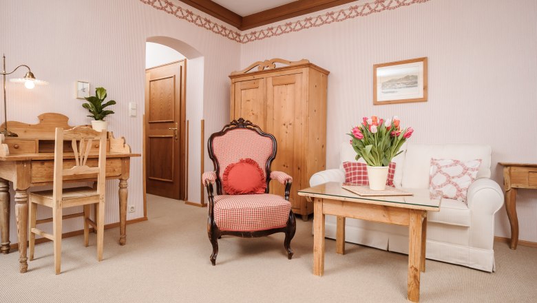 &Uacute;tuln&aacute; ob&yacute;vacia izba s dreven&yacute;m n&aacute;bytkom, kreslom, pohovkou a stol&iacute;kom s tulip&aacute;nmi.