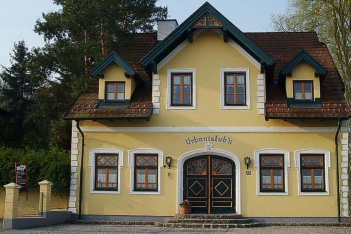 Žltá budova s nápisom "Urbanistubn", obklopená stromami.