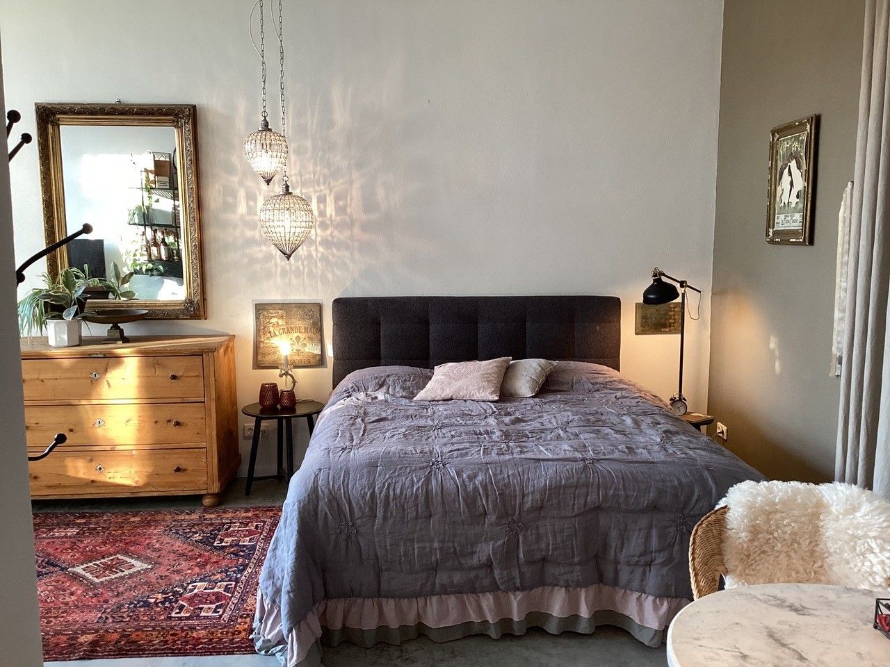 Útulná spálňa s manželskou posteľou, dreveným nábytkom a orientálnym kobercom.