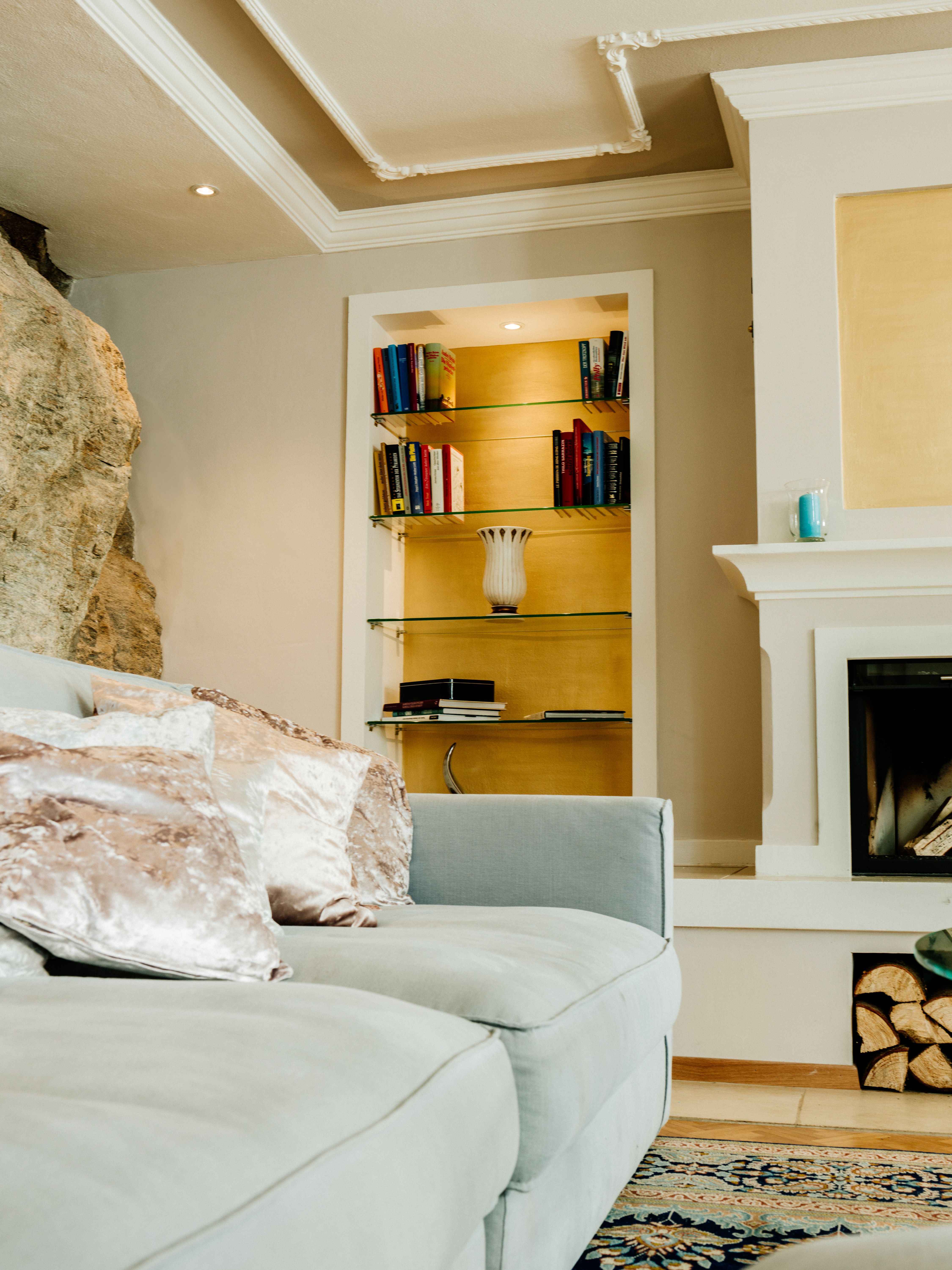 Elegantná obývacia izba so sivou pohovkou, policou na knihy a krbom.