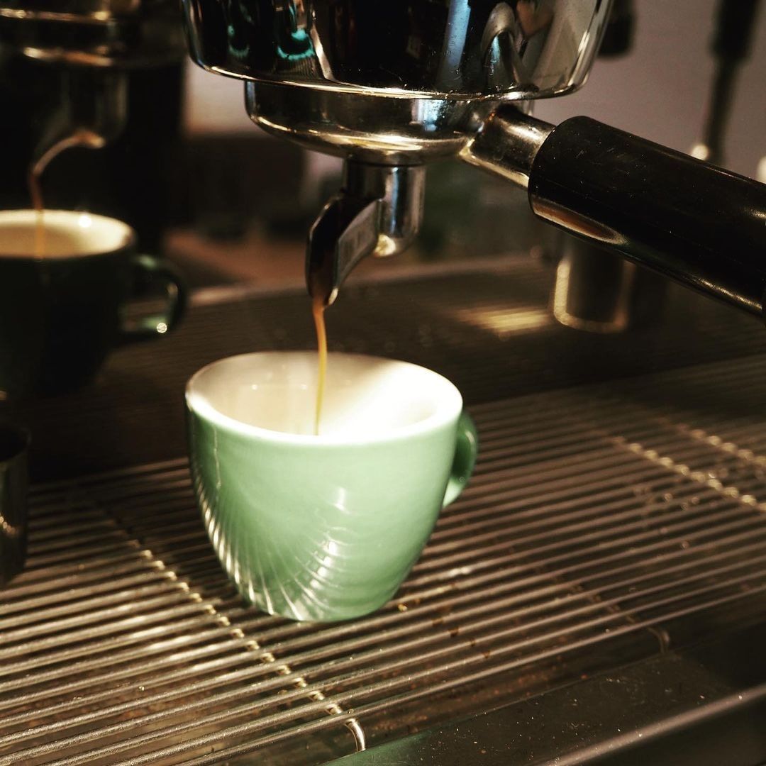 Espresso stroj naplní zelenú šálku kávou.