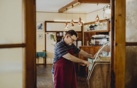 Muž v &uacute;tulnej ob&yacute;vačke obsluhuje jukebox.