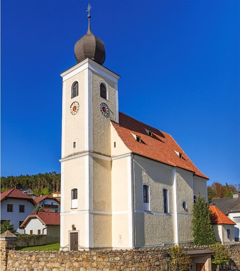 Hollenthonský farský kostol s cibuľovou kupolou a modrou oblohou.