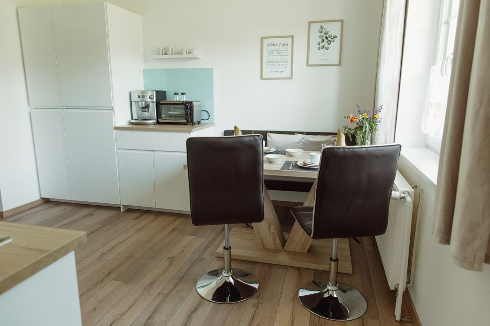 Moderná kuchyňa s jedálenským stolom, stoličkami a spotrebičmi.