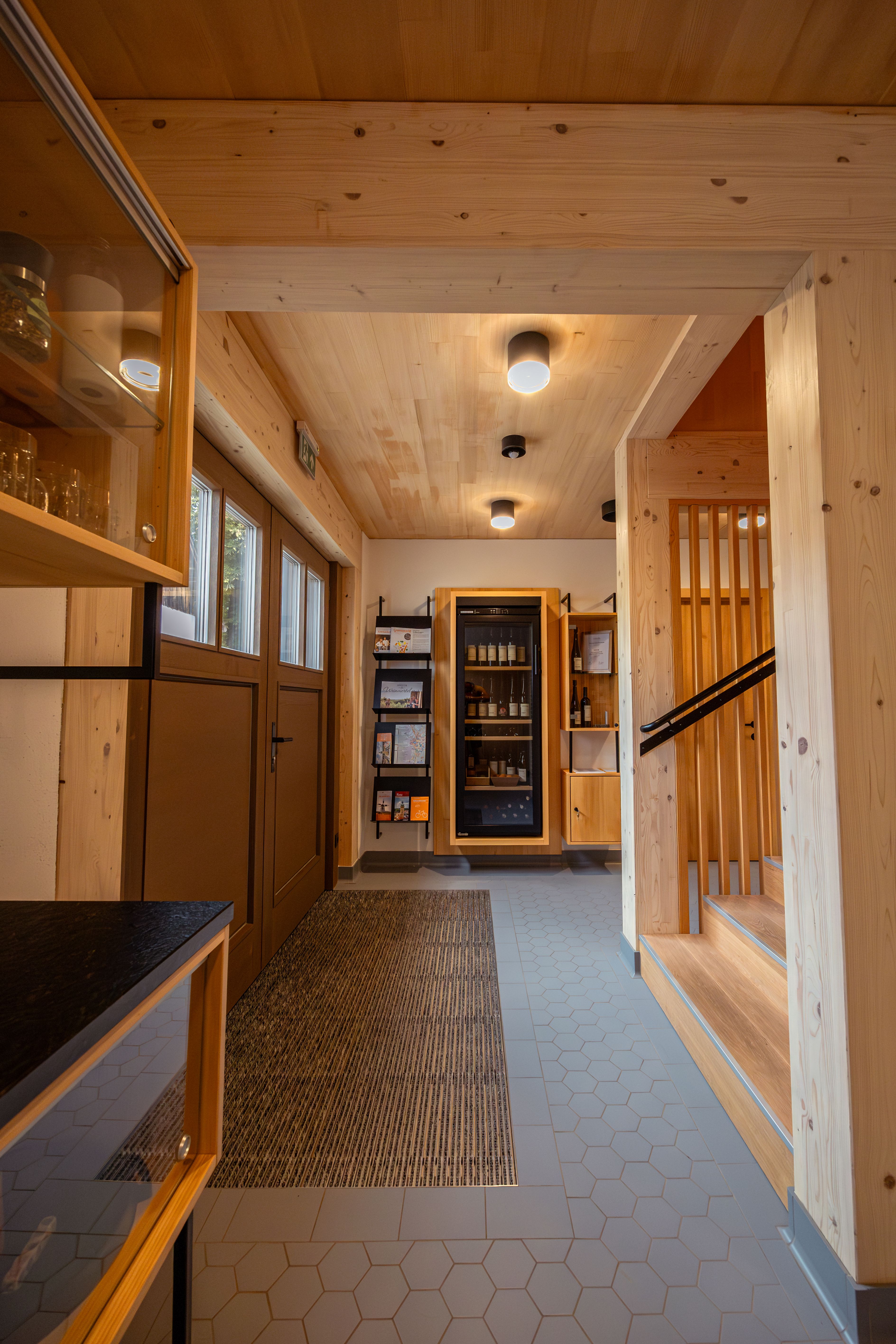 Moderná pivnica vo Weinvierteli za súmraku, obklopená viničom a záhradou. Nápis "Dovolenka na farme".