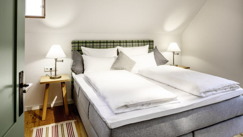 Útulná hotelová izba s manželskou posteľou, nočnými stolíkmi a lampami.