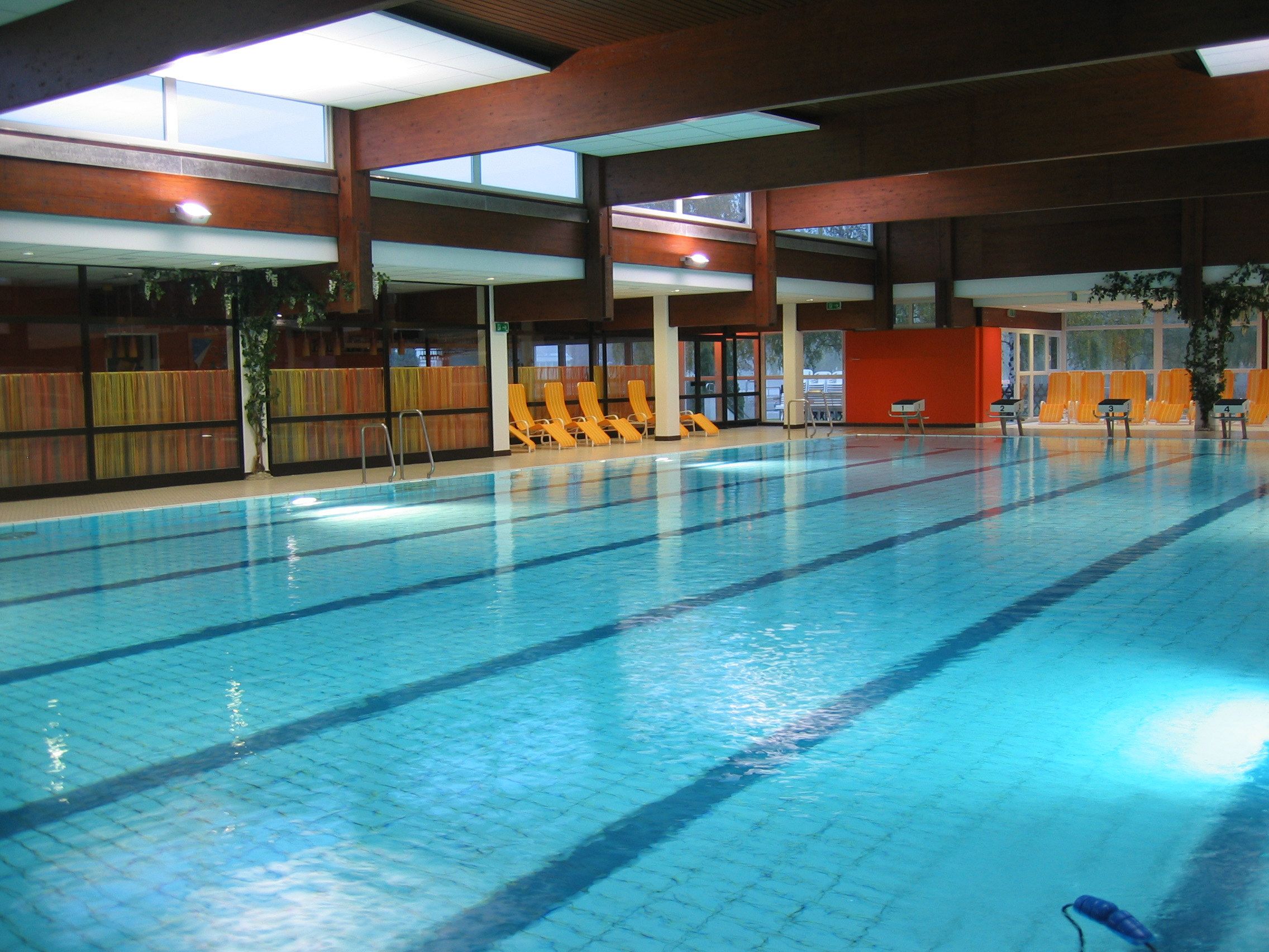 Pohľad do interiéru bazéna s prázdnymi ležadlami na okraji bazéna.