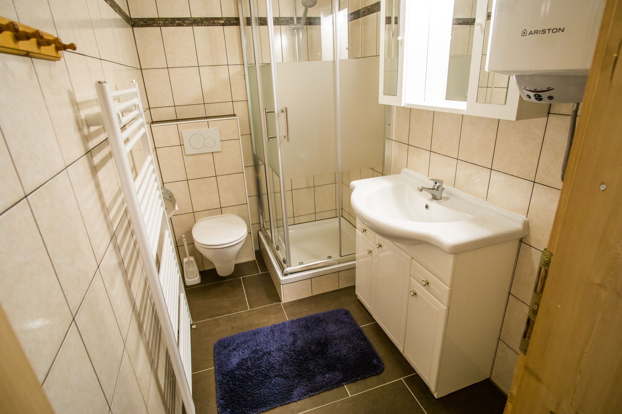 Kúpeľňa so sprchovacím kútom, umývadlom, WC a radiátorom na uteráky.
