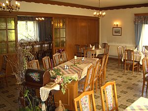 Pohľad do interiéru tradičného hostinca s dreveným nábytkom a zdobenými stolmi.