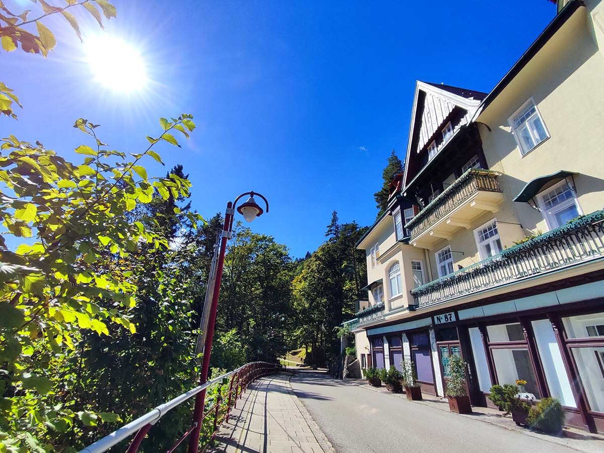 Slnečný deň pred vilou s balkónom a stromami.