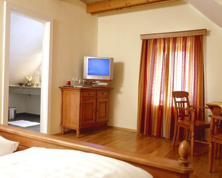 Útulná izba s dreveným nábytkom, TV a farebnými závesmi.