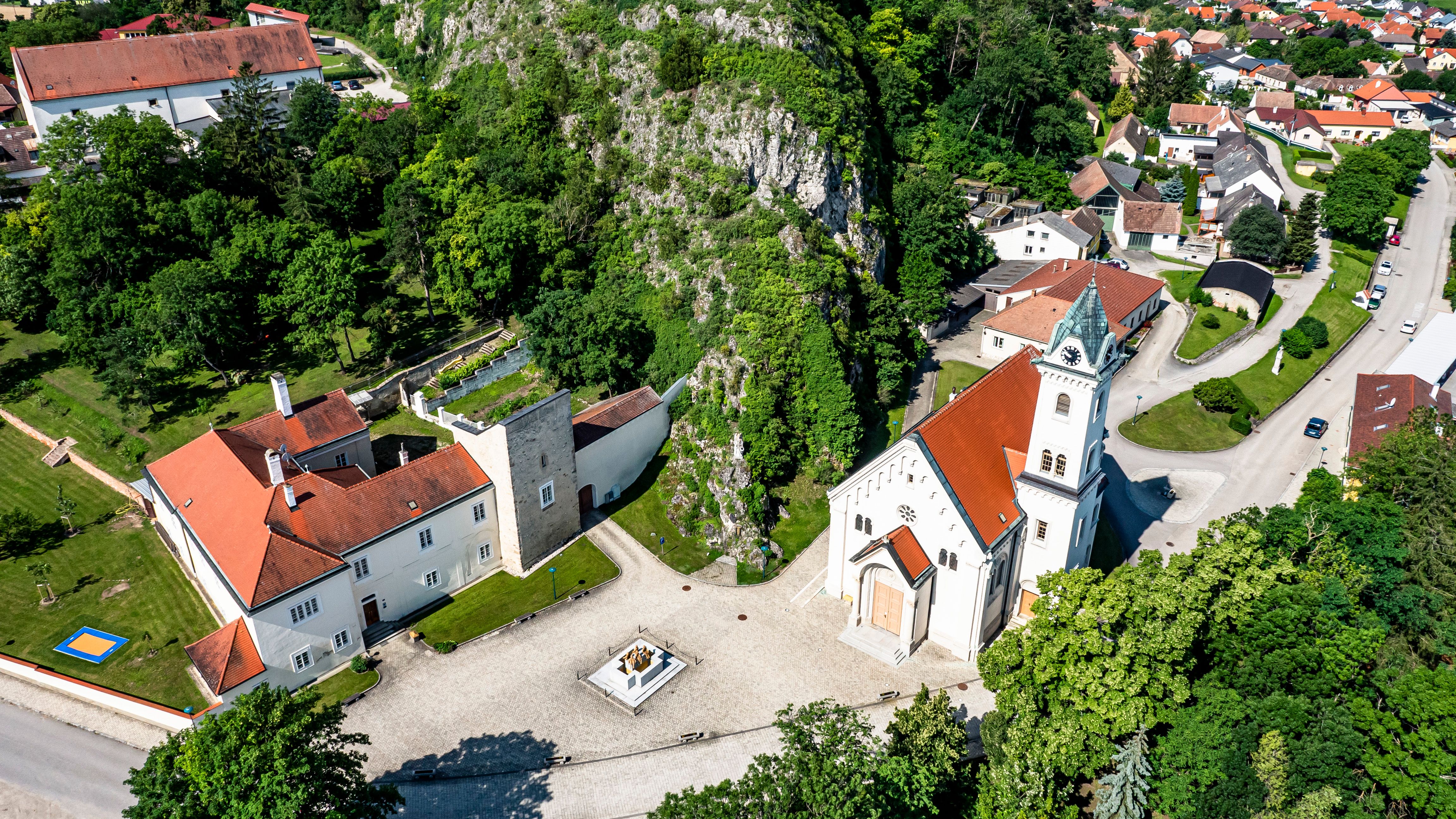 Letecký pohľad na farský kostol Staatz s okolitými budovami a zelenými plochami.