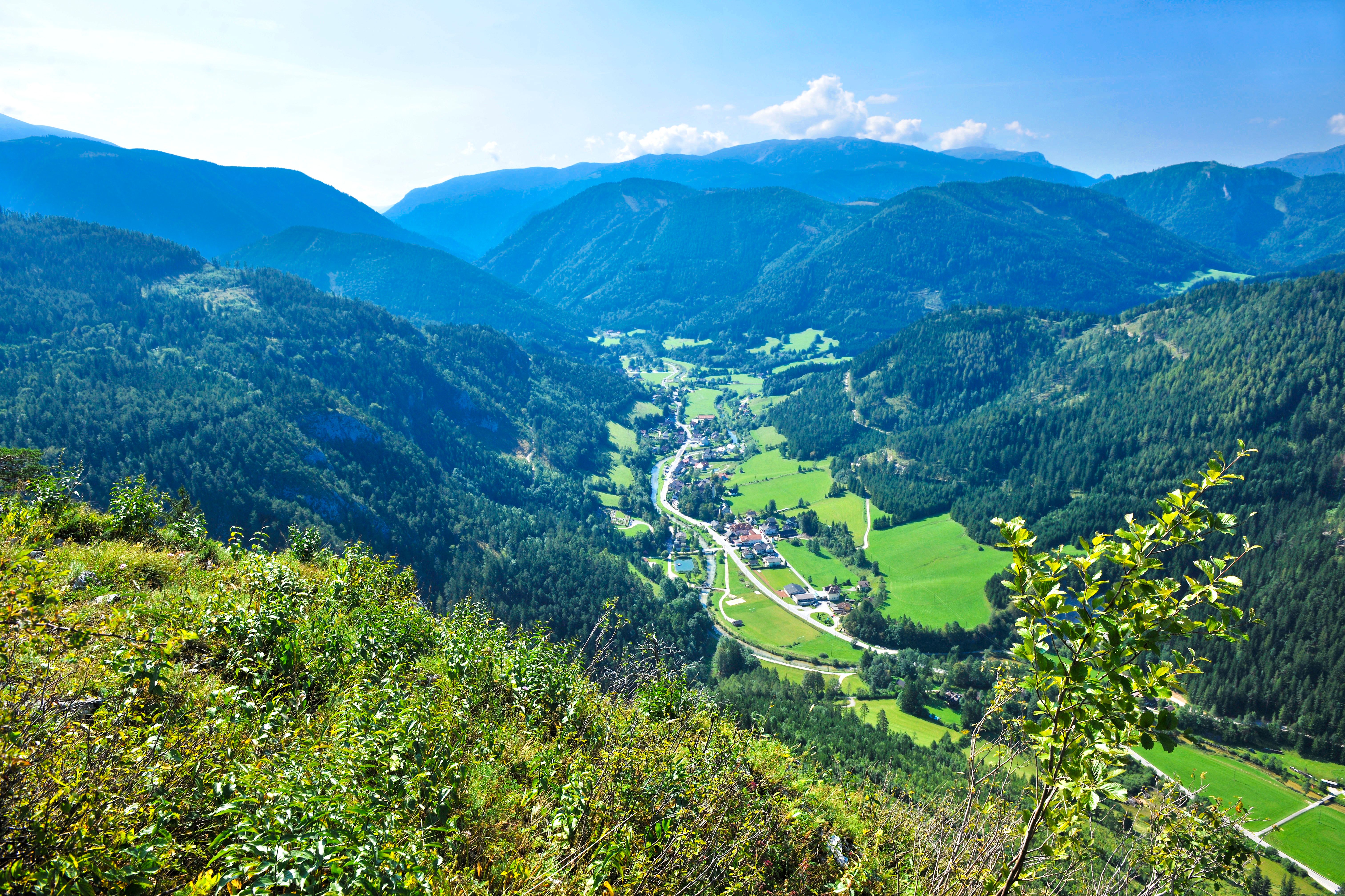 Panoramatický pohľad na zelené údolie s horami v pozadí.
