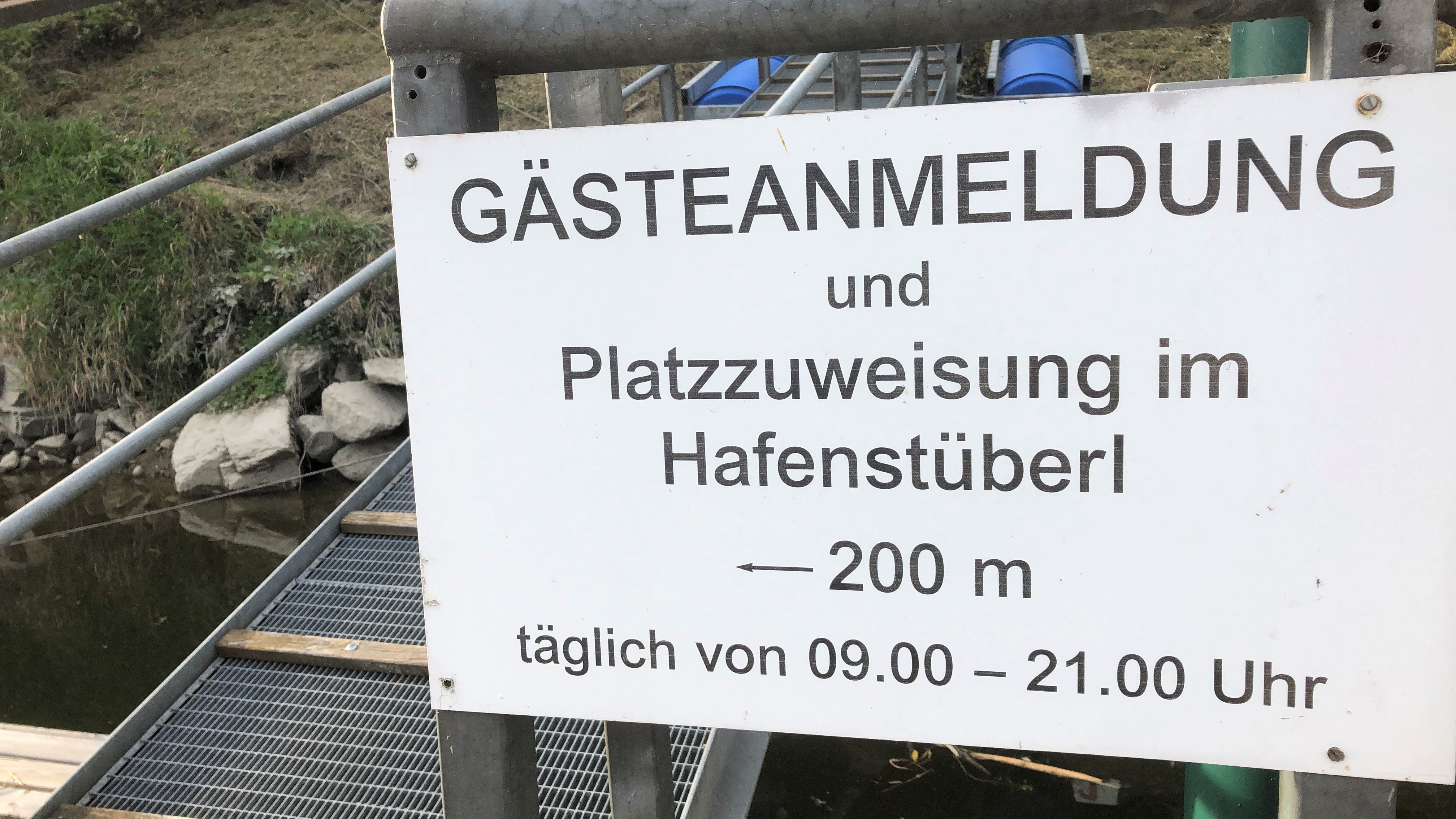 Tabuľka s nápisom "Registrácia hostí a prideľovanie miest v Hafenstüberl, 200 m, denne od 9.00 do 21.00 hod.".