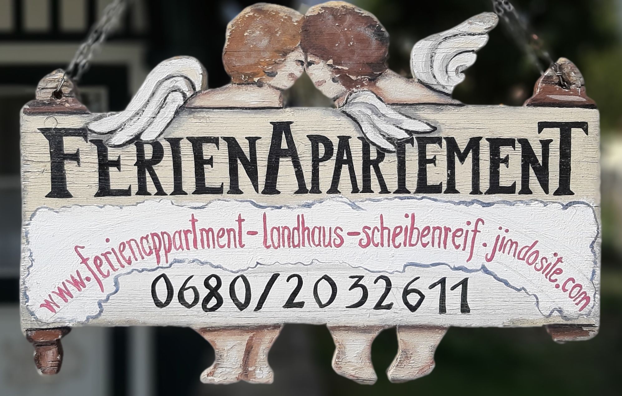 Drevená tabuľka s nápisom "Holiday apartment" a dvoma anjelmi.