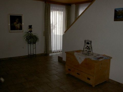 Pohľad do interiéru obytného priestoru s dreveným boxom, rastlinou a schodiskom.