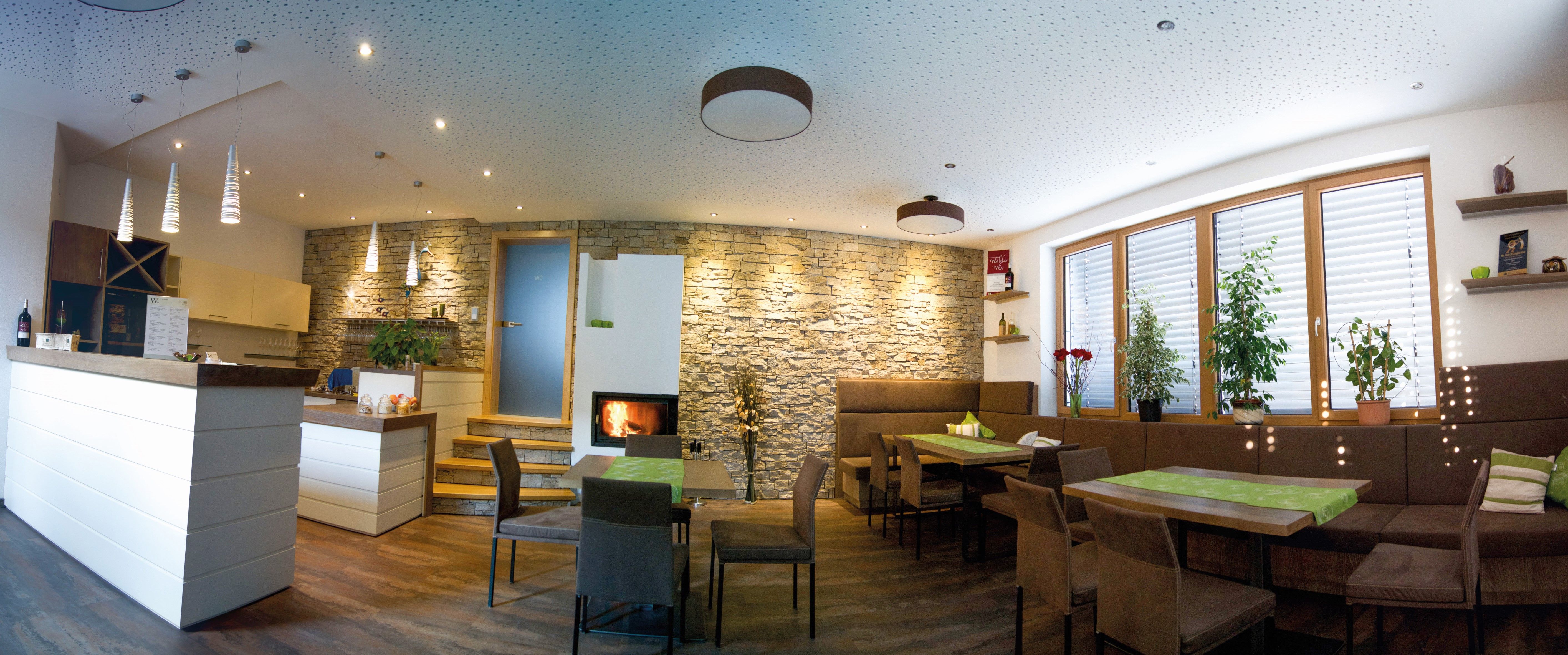 Moderná degustačná miestnosť s dreveným nábytkom, kamennou stenou, krbom a rastlinami.