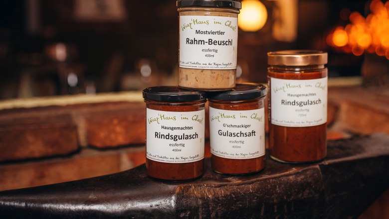 Tri nádoby s hotovými jedlami na kovadline s nápisom "Wirtshaus im Glas".