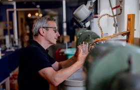 Muž pracuje na skle pri br&uacute;ske v dielni.