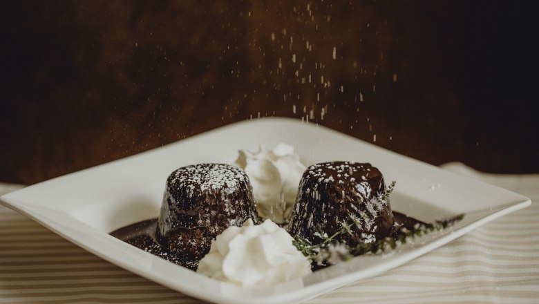 Dva čokol&aacute;dov&eacute; kol&aacute;če s pr&aacute;&scaron;kov&yacute;m cukrom a kr&eacute;mom na tanieri.