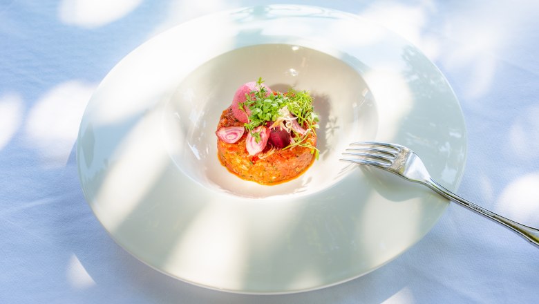 Umne naaranžovan&yacute; pokrm na bielom tanieri a vedľa neho vidlička.