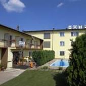 Exteriérový pohľad na žltý hotel s bazénom a záhradou.