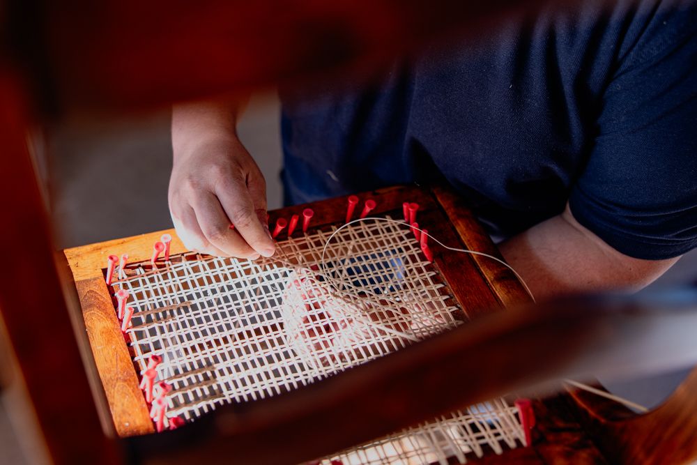 Osoba opravuje stoličku Thonet s viedenským výpletom.