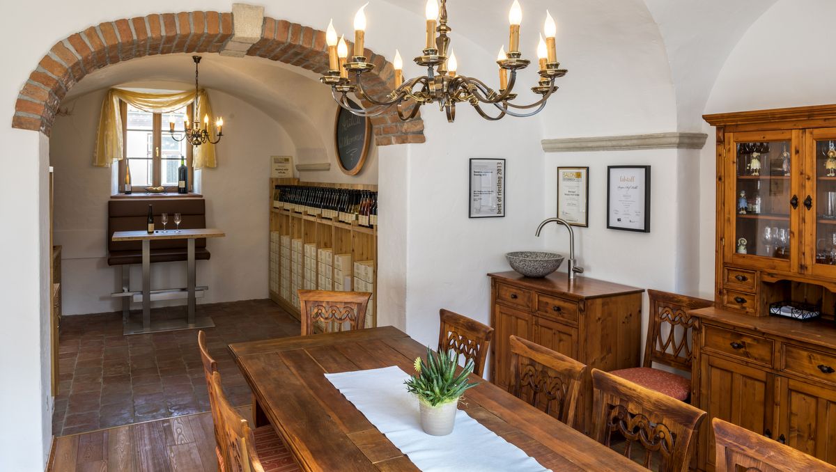 Útulná izba s dreveným nábytkom, lustrom a stojanom na víno.