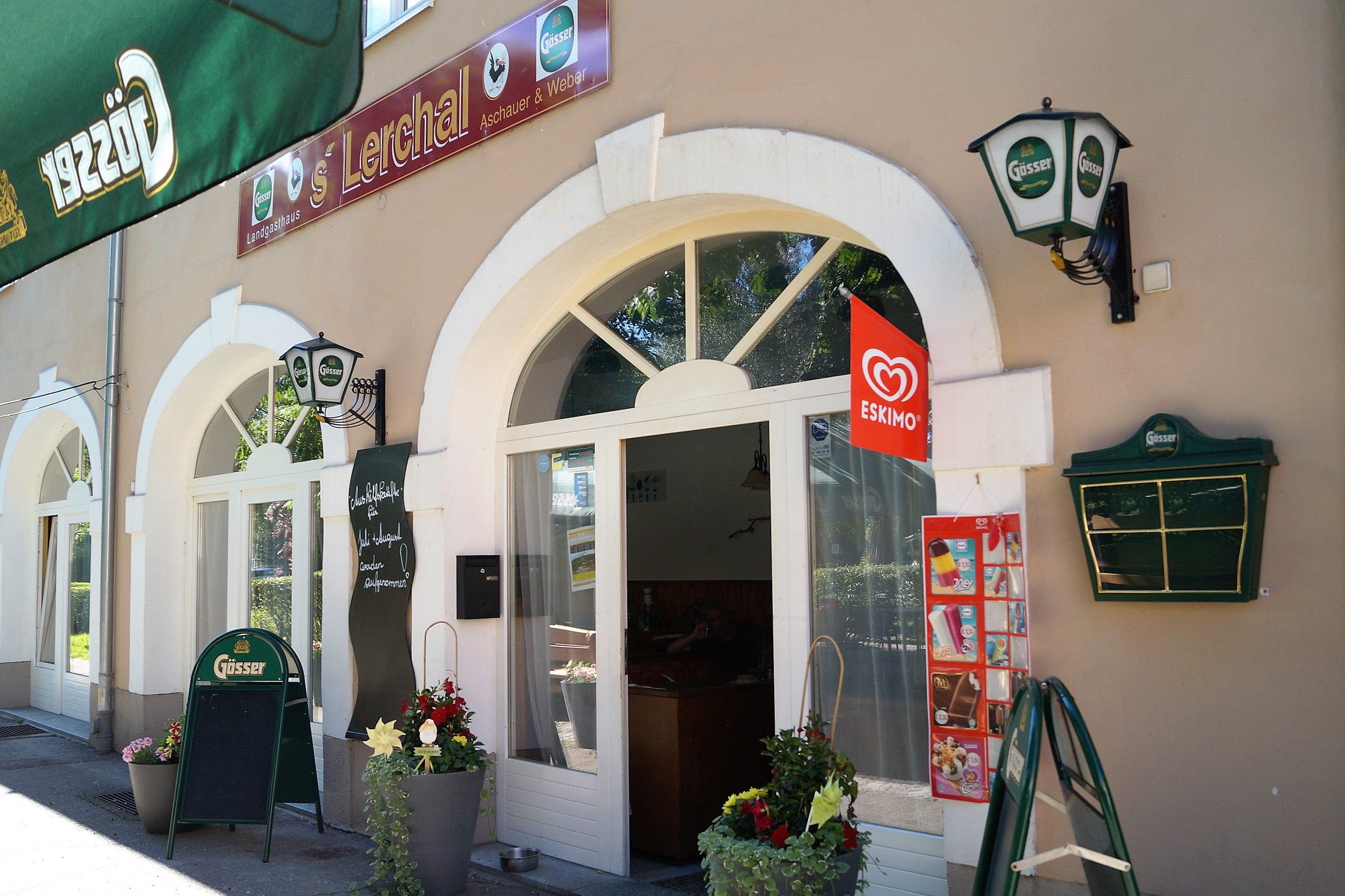 Exteriérový pohľad na reštauráciu s nápismi Gösser a reklamou na zmrzlinu Eskimo.