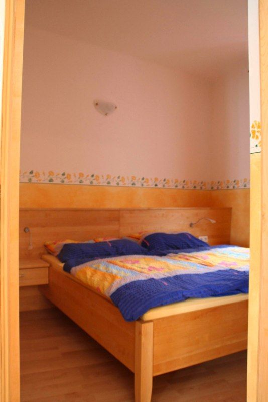 Spálňa s drevenou posteľou a farebnou posteľnou bielizňou.