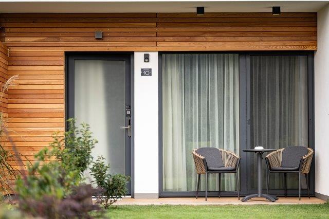 Moderná terasa s dvoma stoličkami a stolom pred penziónom.