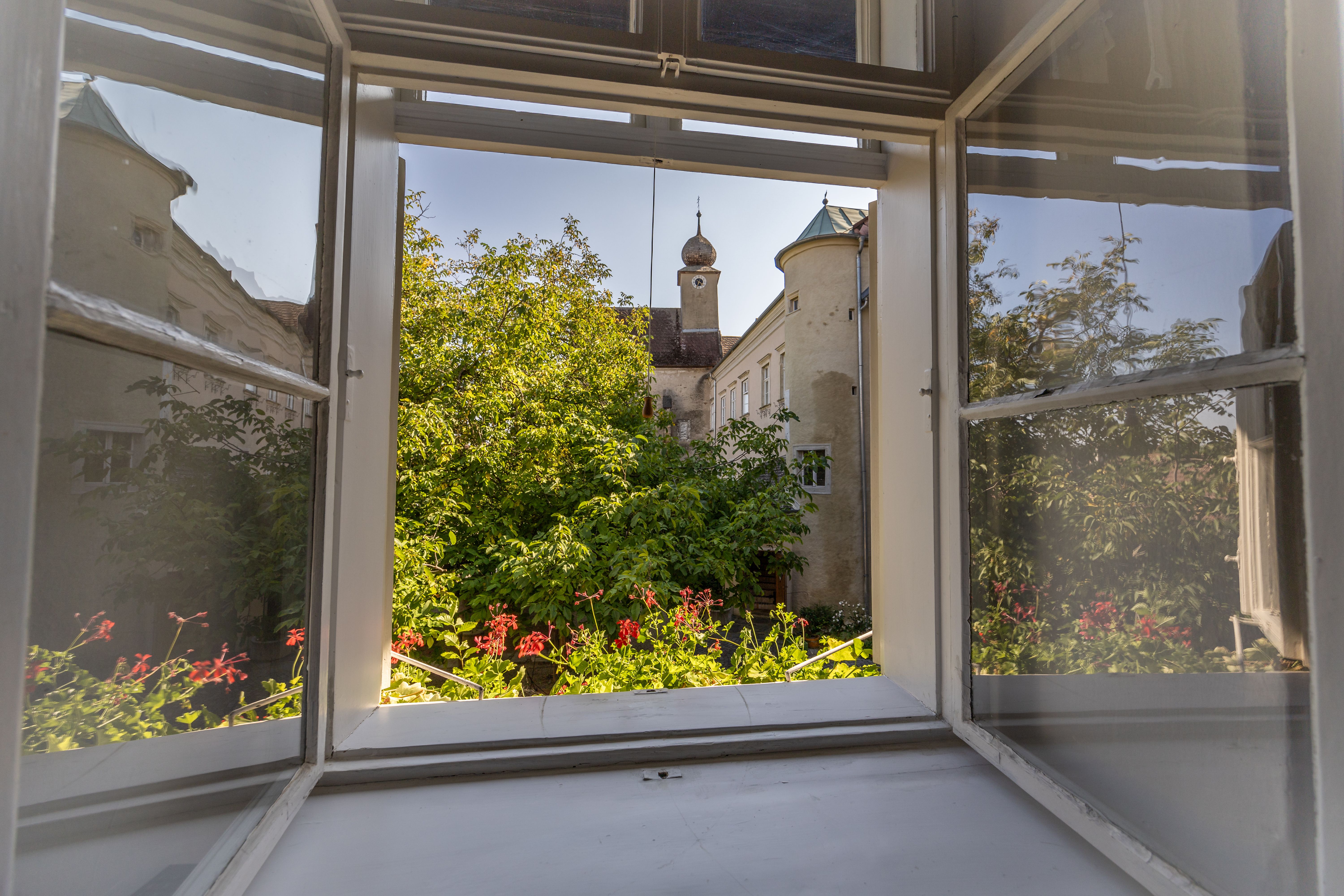 Spálňa s klenutým stropom, drevenou podlahou, posteľou, kreslom, komodou a kožušinovým kobercom.