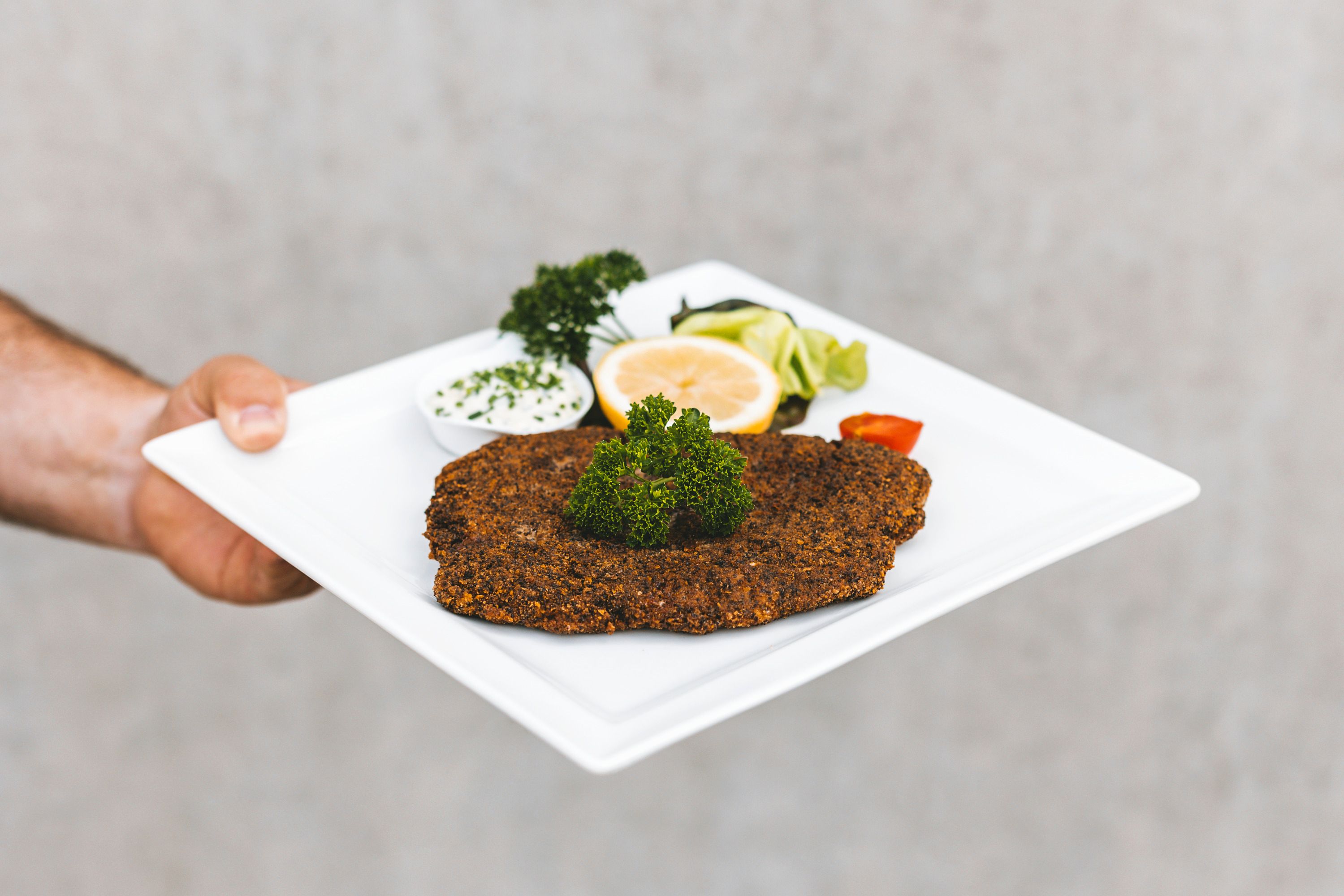 Tanier s obalenou rybou, citrónom, petržlenovou vňaťou a dipom.