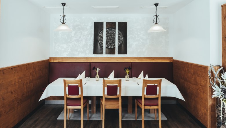 &Scaron;t&yacute;lovo prestret&yacute; st&ocirc;l v re&scaron;taur&aacute;cii s dreven&yacute;m obložen&iacute;m a modern&yacute;m umen&iacute;m na stene.