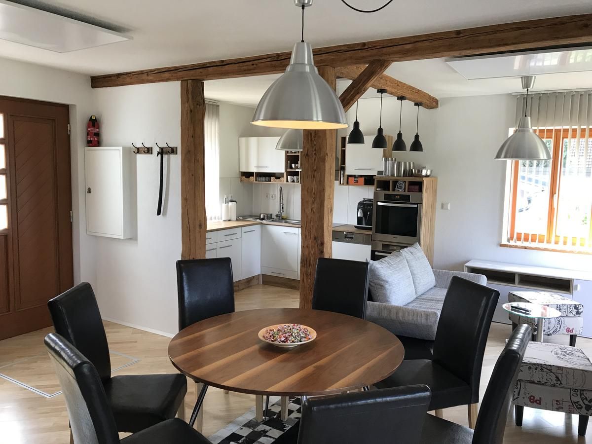 Moderný obývací priestor s jedálenským stolom, stoličkami, kuchyňou a pohovkou.