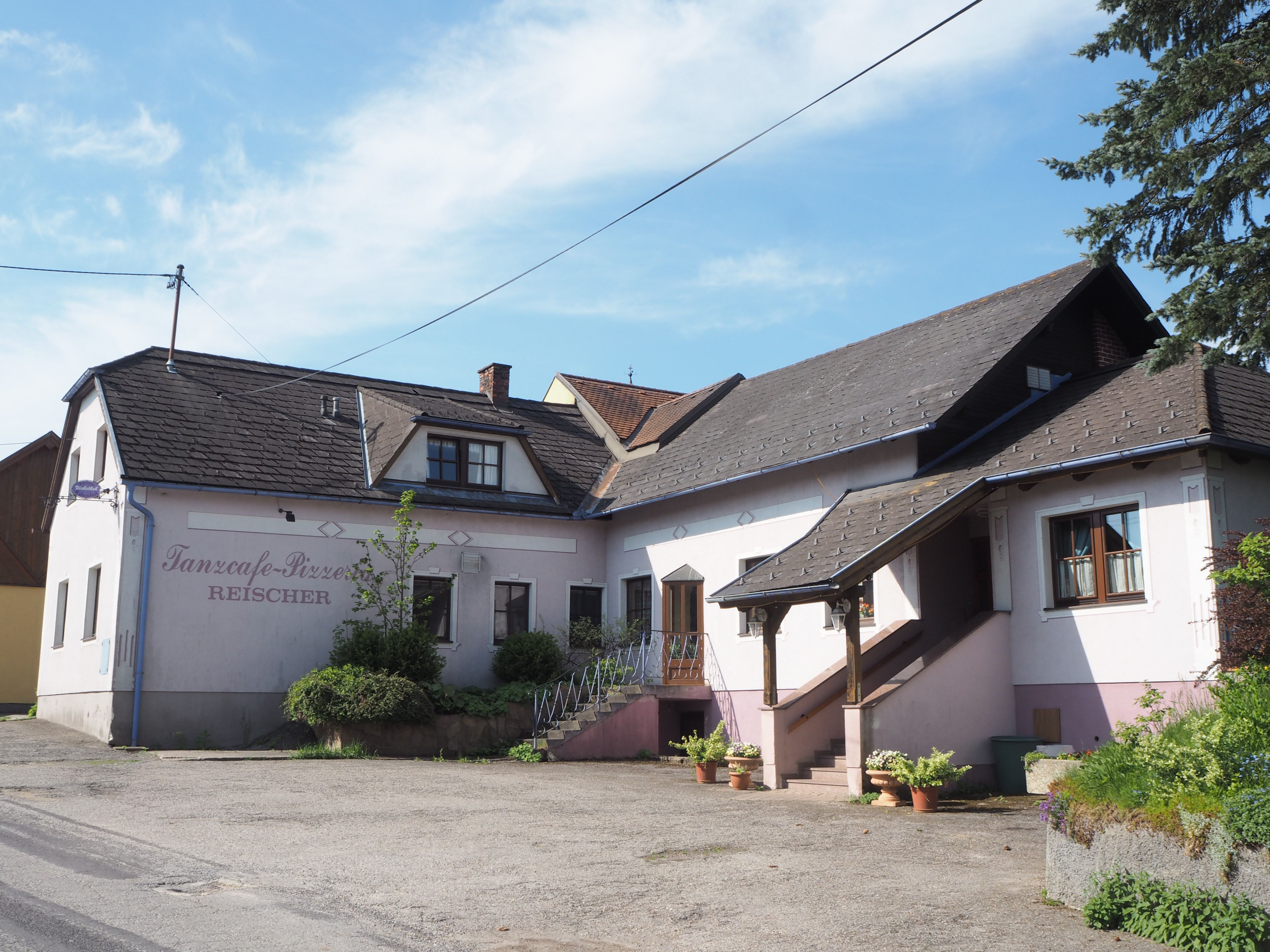 Pohľad zvonku na budovu s označením "Tanzcafe-Pizzeria Reischer".