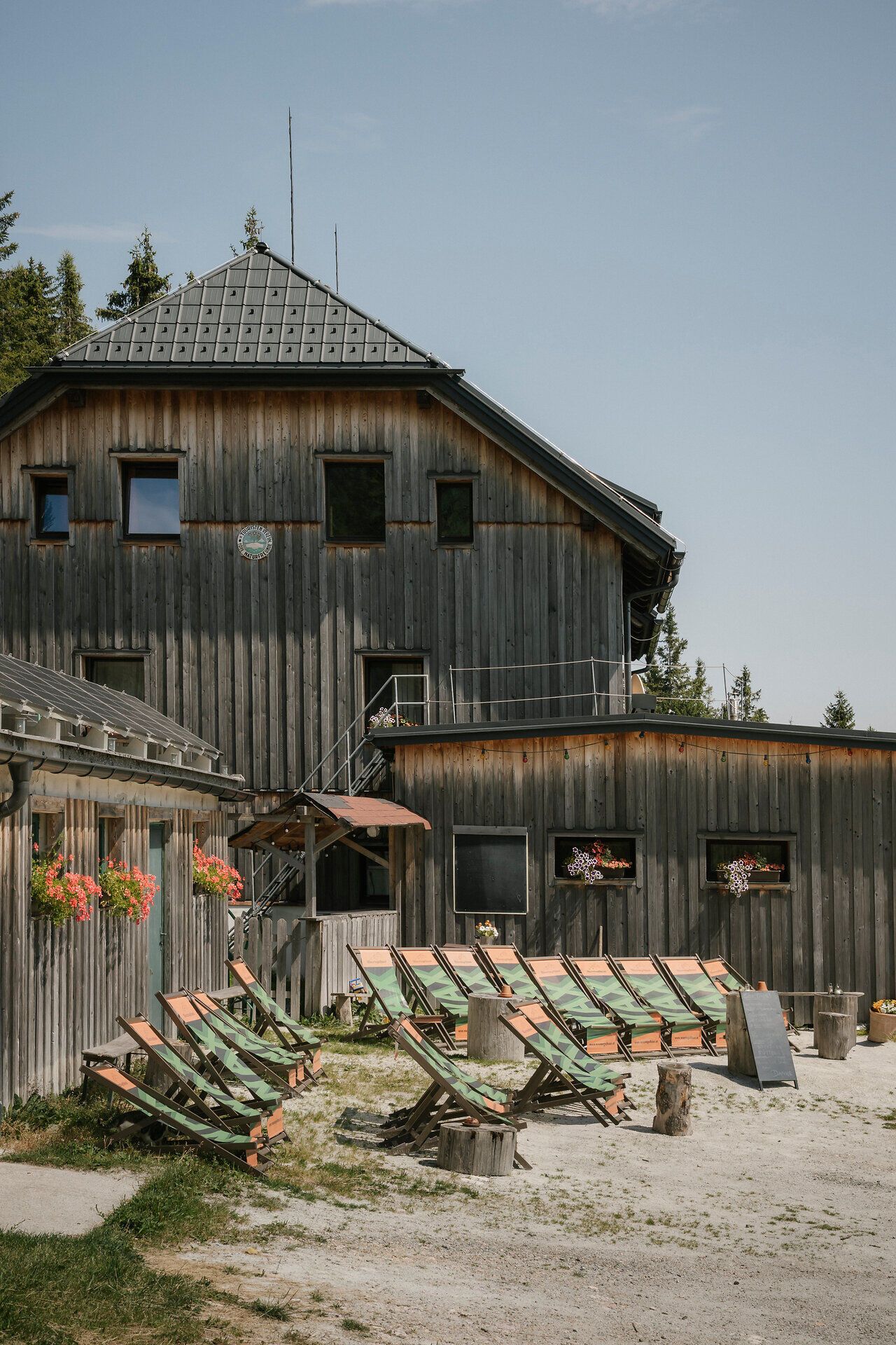 Drevenica vo štýle „Waxriegelhaus“ na vrchu Rax s ležadlami pred tradičnou drevenou budovou