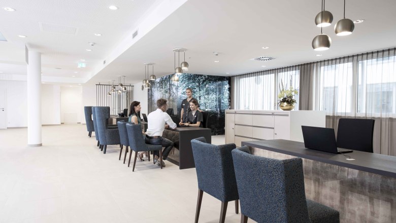 Modern&aacute; recepcia s ľuďmi, ktor&iacute; sedia pri stole a rozpr&aacute;vaj&uacute; sa.