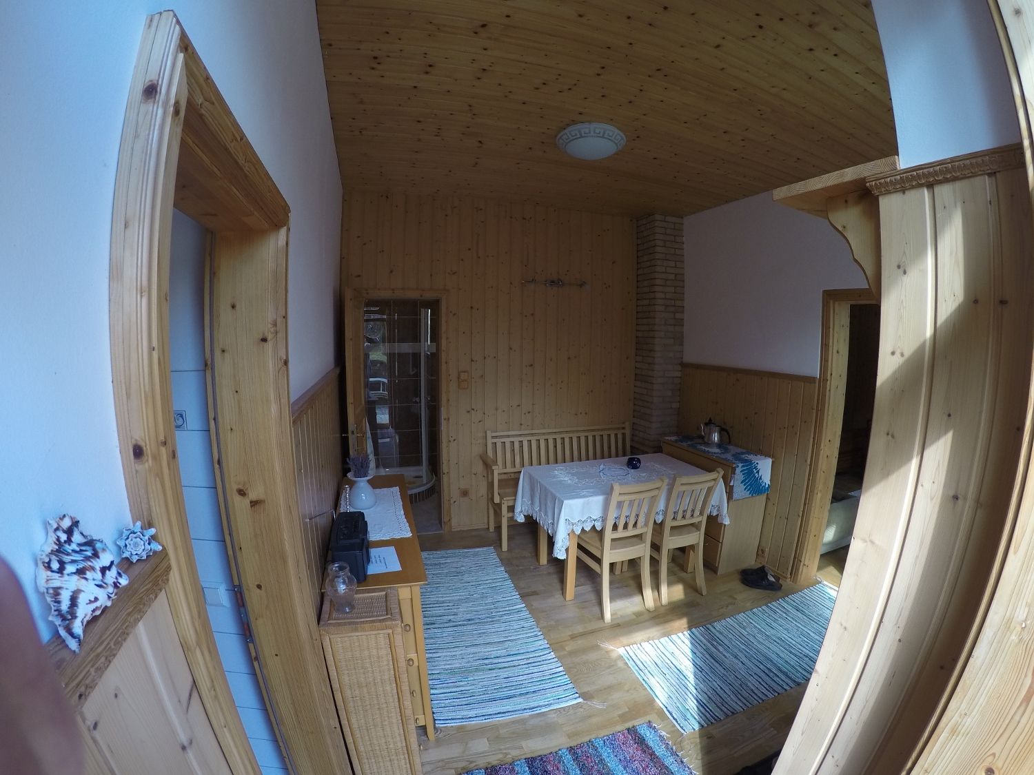 Jedáleň s drevenými stenami, stolom a stoličkami, kobercami a dekoráciami.