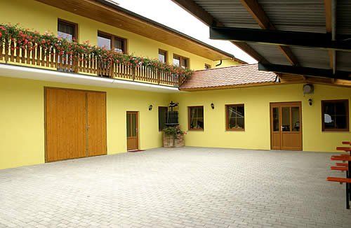 Vnútorný dvor žltej budovy s drevenými dverami a balkónom s kvetmi.