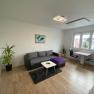 Living room with sofa, pictures on the wall and large window, © Kathi Brandstetter