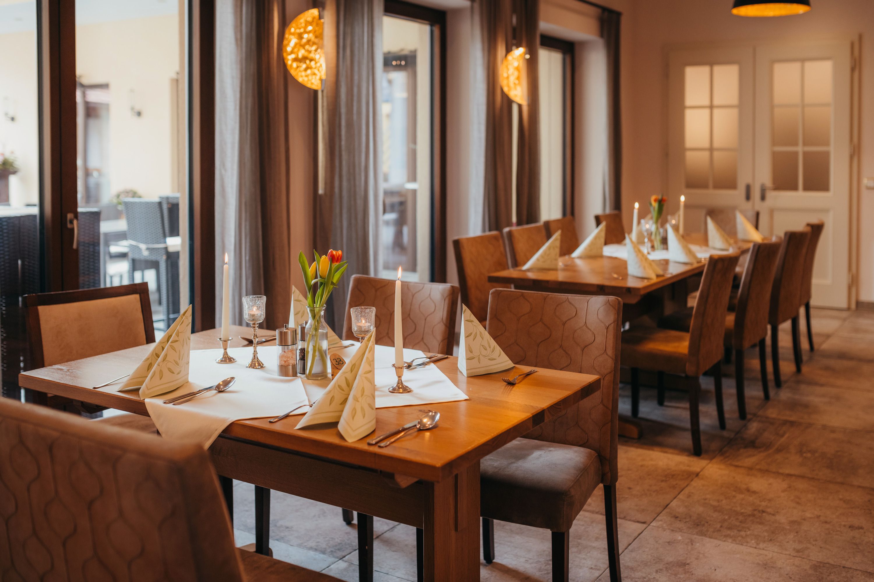 Útulný stôl v krčme so sviečkami a kvetmi.