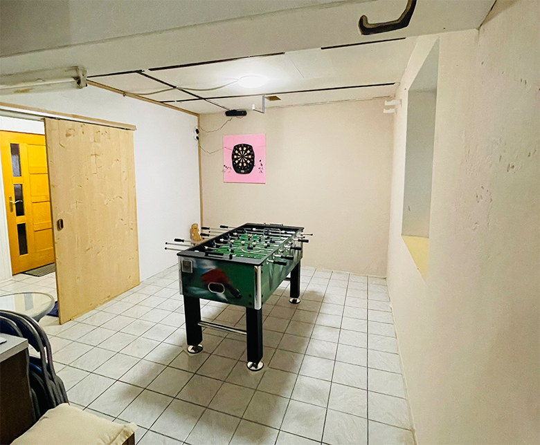 Herňa so stolným futbalom a šípkami na stene.