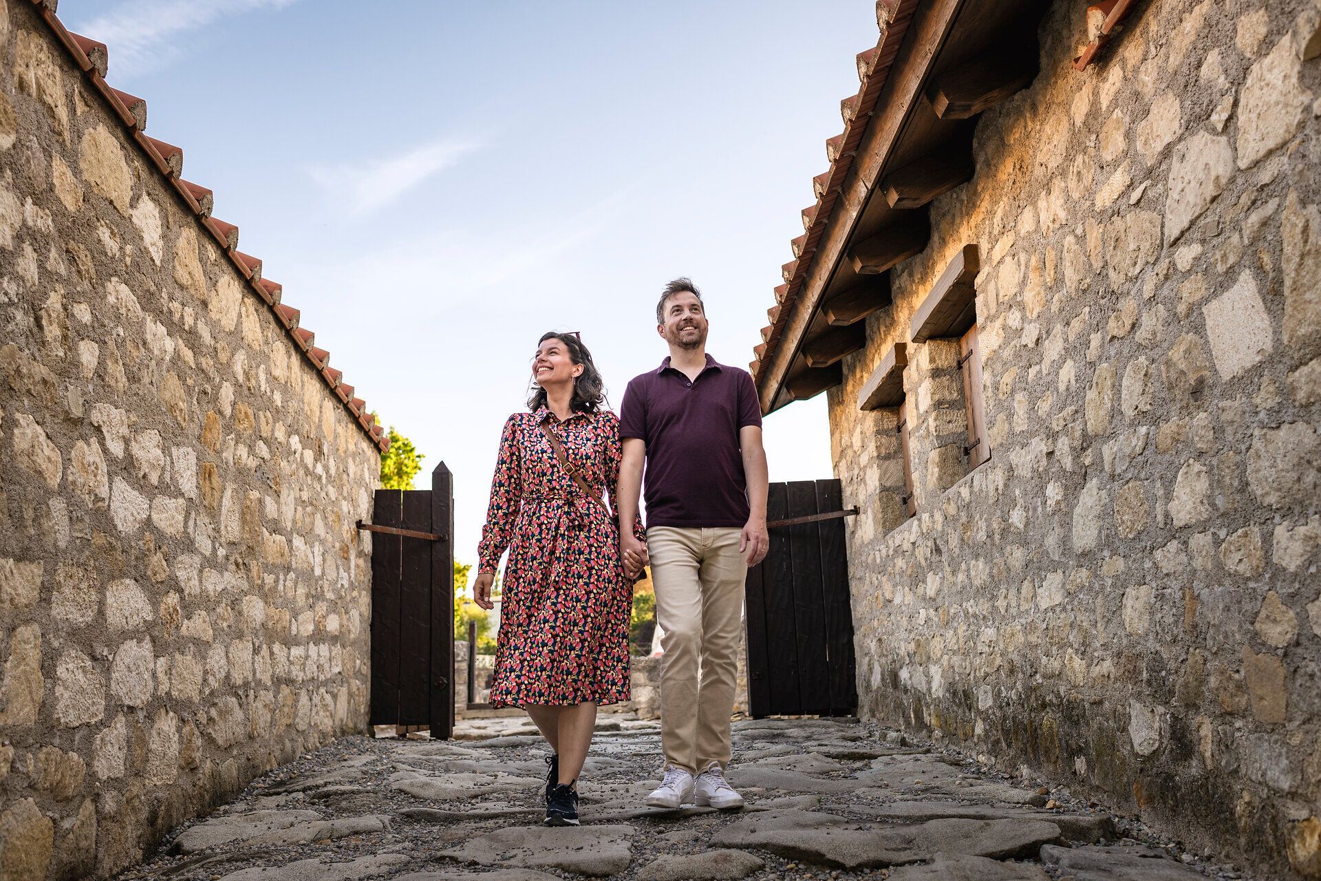 Pár na prechádzke rímskou štvrťou rímskeho mesta Carnuntum. Kamenné domy vľavo a vpravo. 