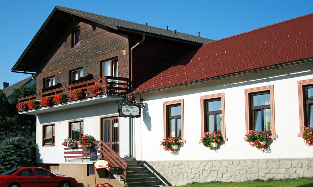 Gasthaus Malzer s balkónom a oknami zdobenými kvetmi.