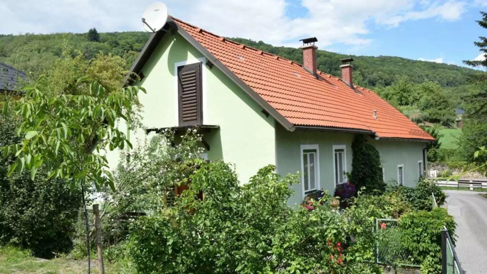 Zelený rodinný dom zvonku s červenou strechou