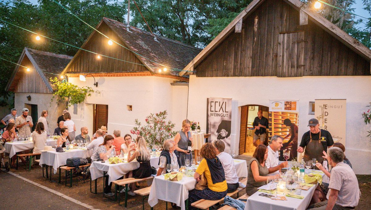 Ľudia sedia pri stoloch pred vinárstvom v Vínnych uličkách.