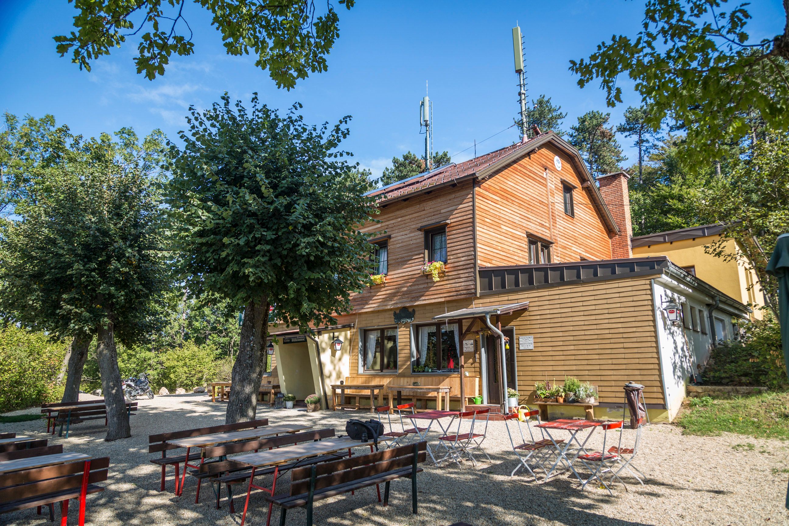 Drevený dom s vonkajšou pivnou záhradou obklopenou stromami.